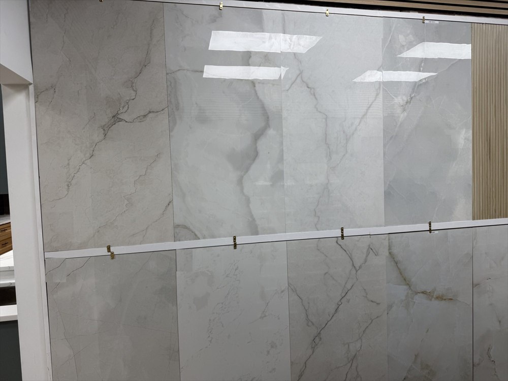 Large-format porcelain tiles with a soft grey marble look on a showroom display wall