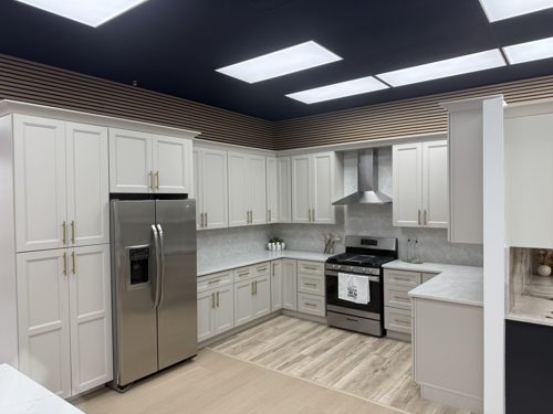 White kitchen cabinets with a stainless steel refrigerator and range hood