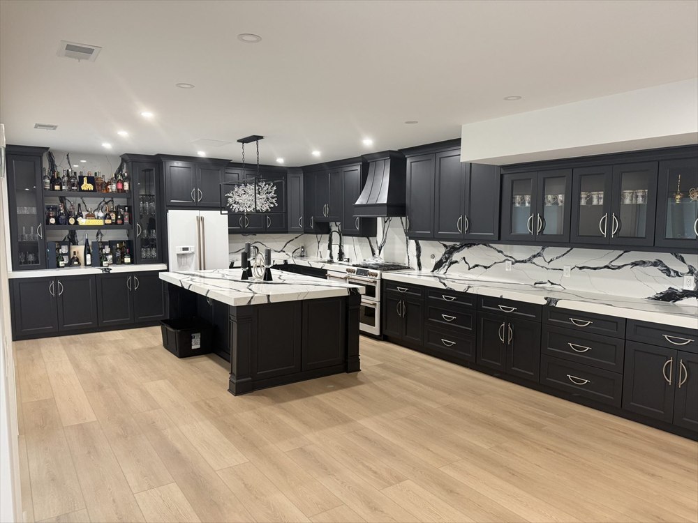 Large kitchen with black shaker cabinets, glass-front uppers, a built-in bar, and white countertops and backsplash with dramatic black veining